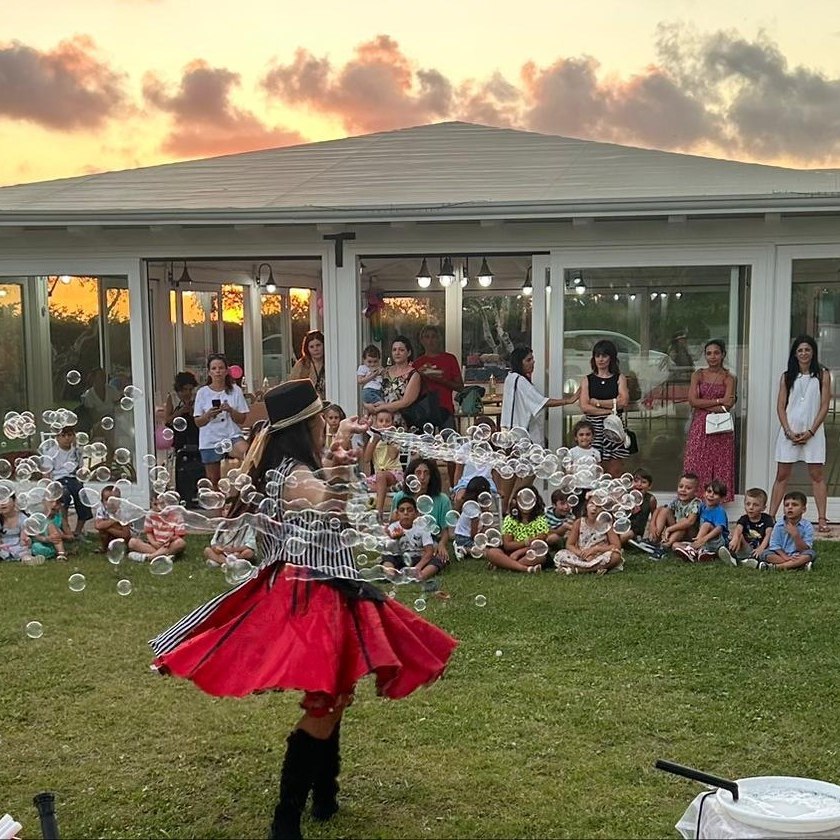 Spettacolo di bolle di sapone davanti ai bambini seduti sotto il gazebo