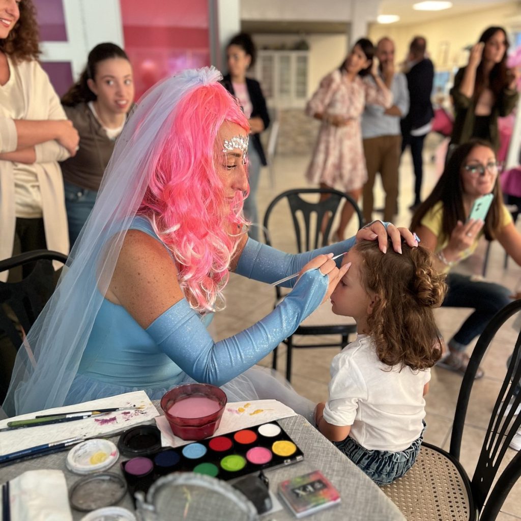 Animatrice trucca il viso di una bambina durante una festa