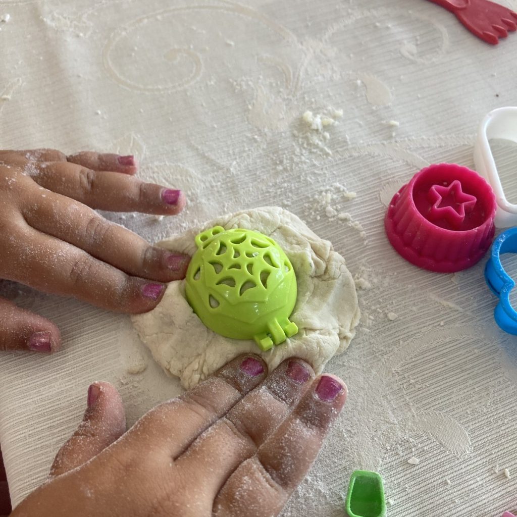 Mani di bambina che modellano la pasta con le formine
